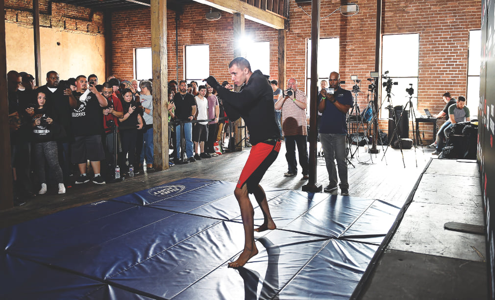 James vick shadow boxing on blue mats with a small crowd watching