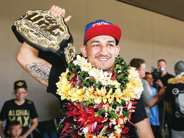 max holloway holding title belt above his head with a cap on