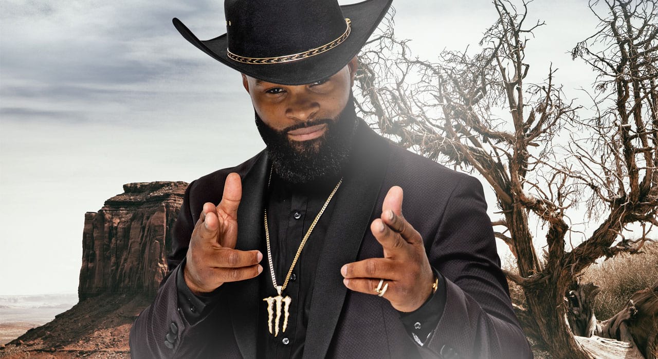 Tyron Woodley in a cowboy hat and monster energy neckplace holding his hands like guns
